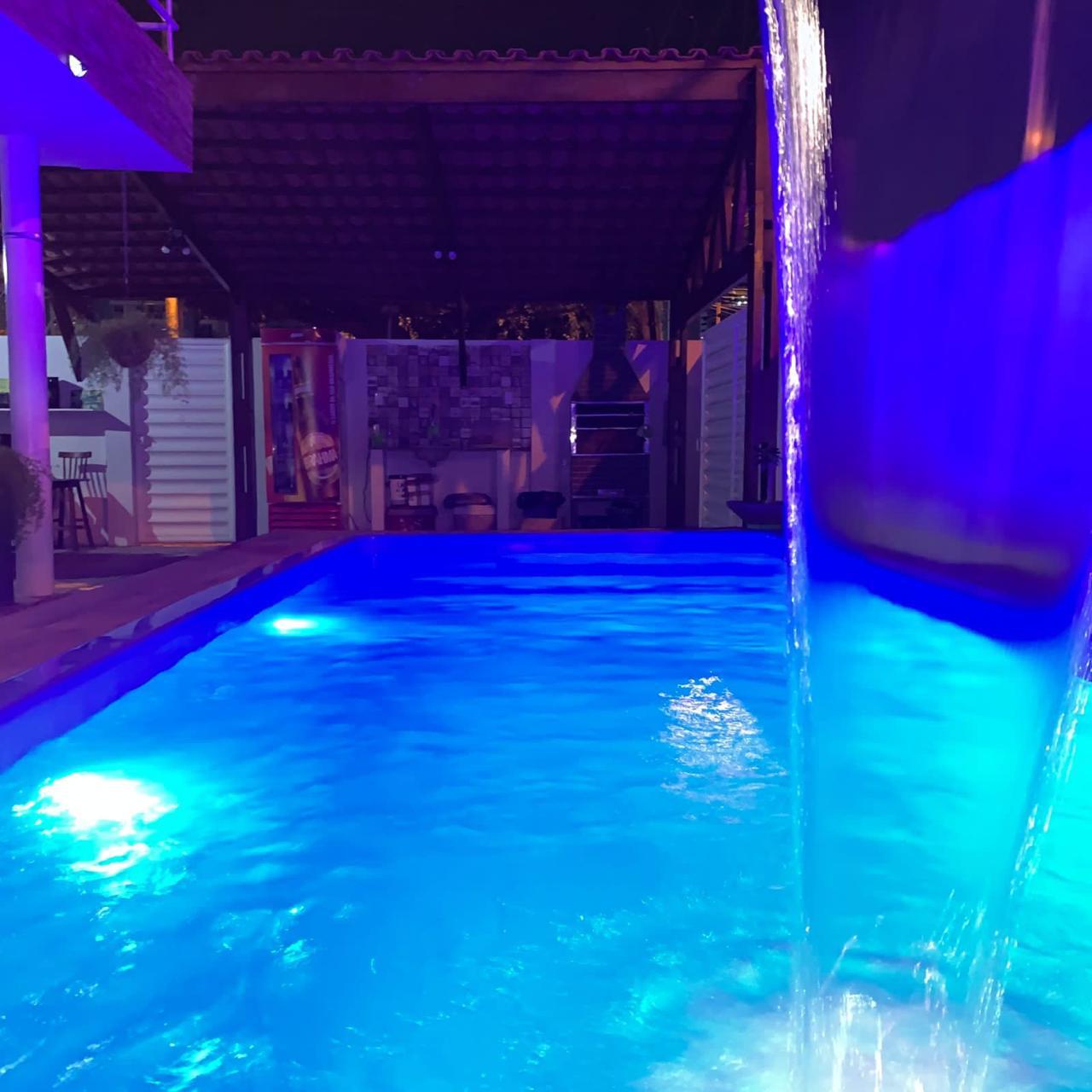 Piscina com cortina d'água em espaço gourmet com churrasqueira