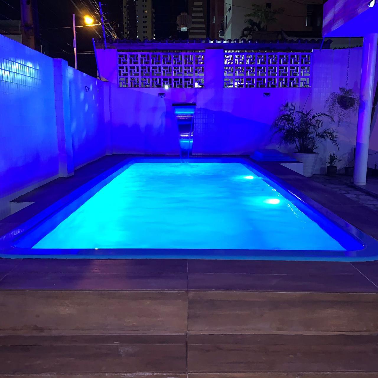 Piscina residencial com cascata em aço inox iluminada à noite