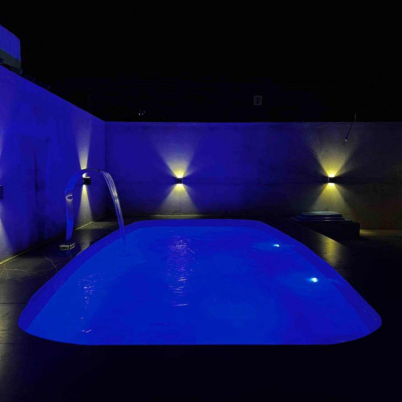 Piscina com iluminação LED azul e cascata em arco