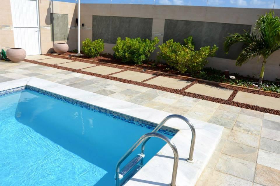 Piscina com deck em pedra natural, passo japonês e paisagismo
