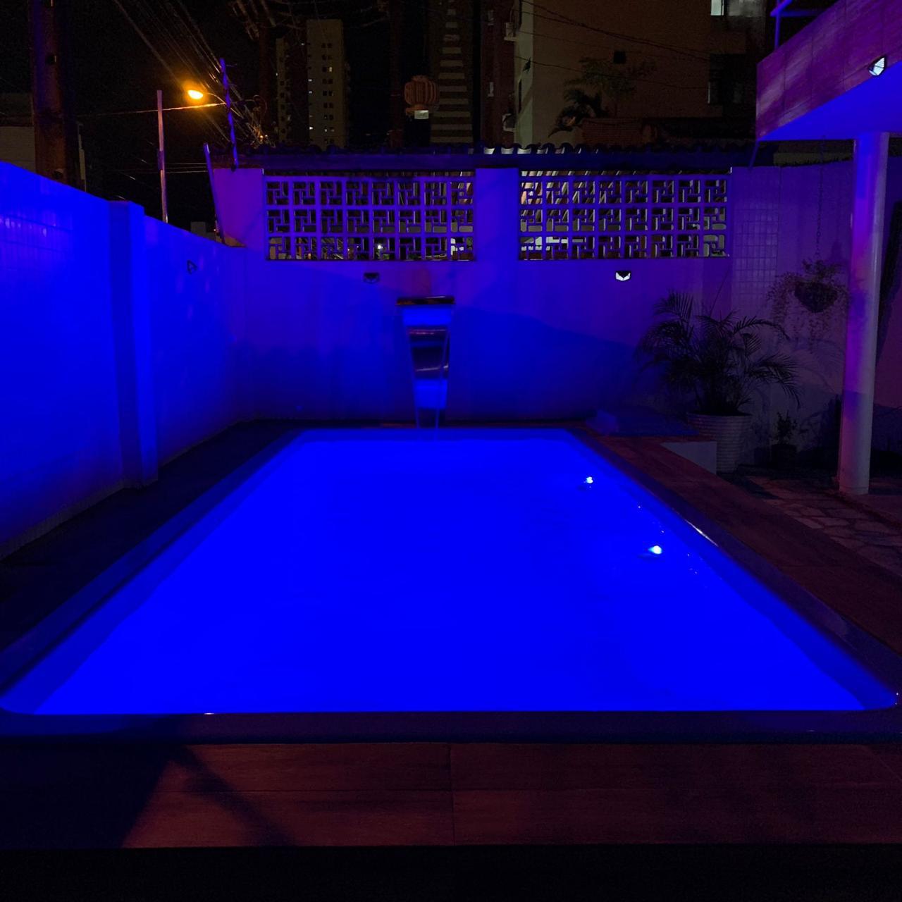Piscina residencial iluminada à noite com cascatas